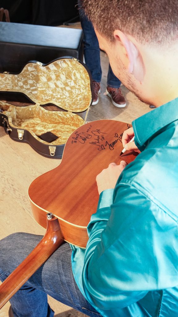 Andrea Valeri signiert eine Akustikgitarre