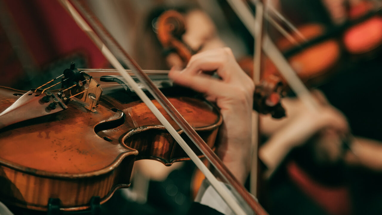 Close-up of a violinist playing in an orchestra during a classical music concert for Thomann blog article: 10 Classical Masterpieces