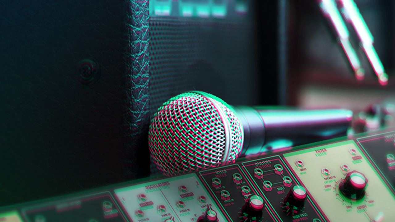 Close-up of a dynamic microphone, guitar amplifier, and synthesizer during a synth recording session for the blog “Recording Synths Through Guitar Amps: 5 Tips”