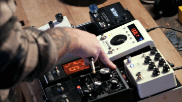 Close-up of guitarist adjusting guitar pedalboard with multiple effects pedals in a studio setup: Pedalboard Basics: How to Set Up and Organize Your Effects Chain