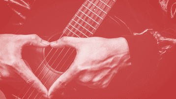Een muzikant vormt een hart met zijn handen over een akoestische gitaar, als symbool van liefde voor muziek op Valentijnsdag.