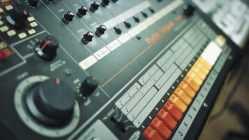 Close-up van de Roland TR-808 drumcomputer met kleurrijke step-sequencerknoppen en analoge bedieningselementen.