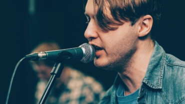 Close-up van een mannelijke zanger die zich vocaal opwarmt bij een microfoon. Is een Vocal Warm-up Echt Nodig? Tips voor Zangers