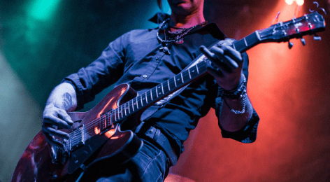 Guitarist playing an electric guitar live on stage with dramatic lighting – focus on guitar riffs